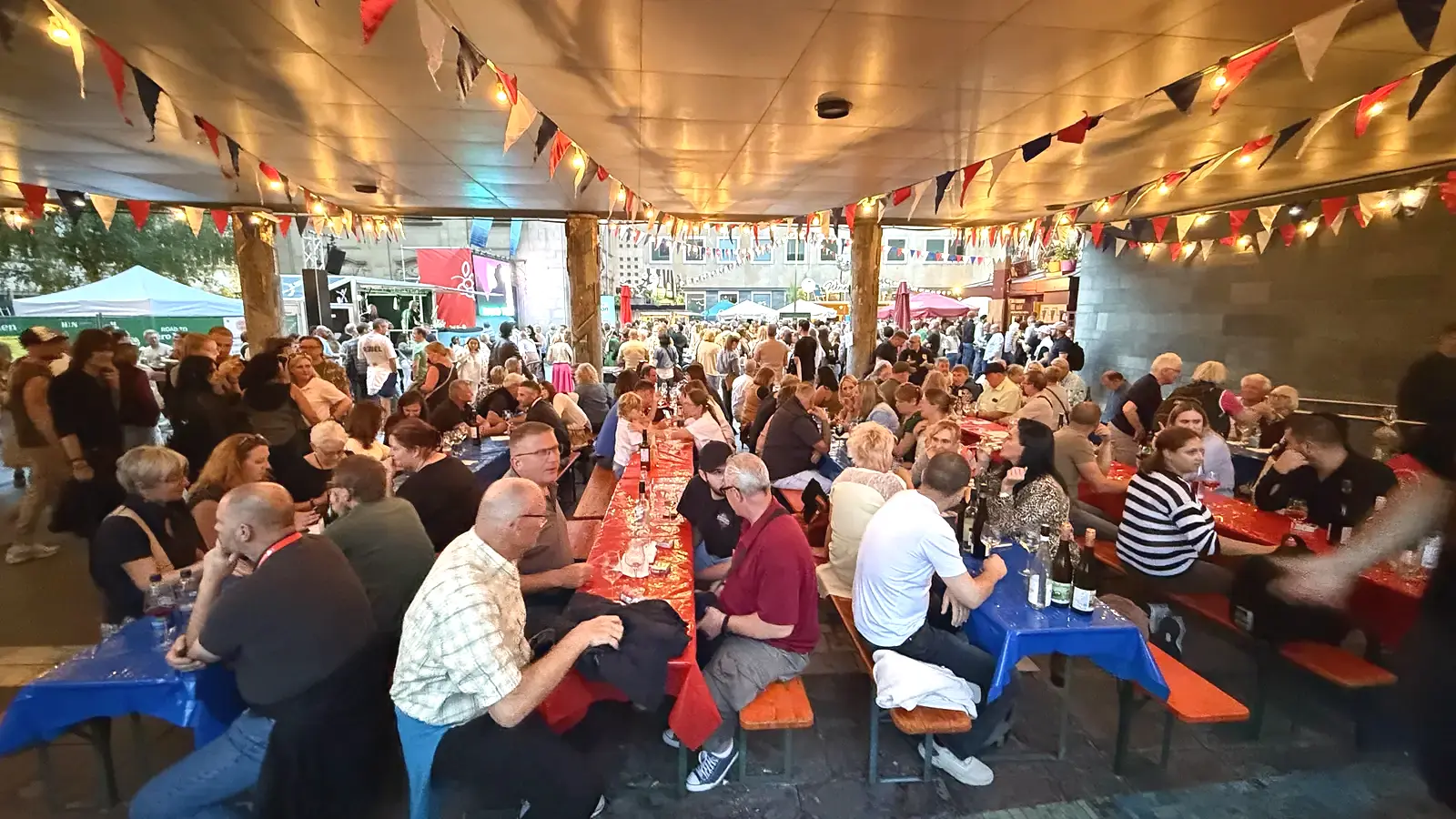 Besucherinnen und Besucher an langen Tischen beim Heilbronner Weindorf