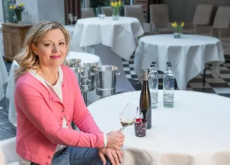 Weinexpertin Natalie Lumpp mit einem Weinglas an einem gedeckten Tisch