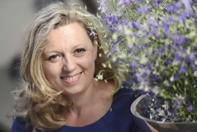 Natalie Lumpp lächelt neben violetten Blüten